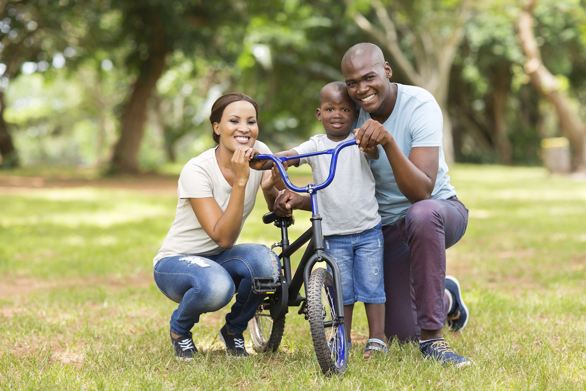 Smiling family with their young son and a bicycle in a park